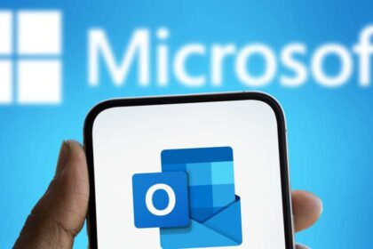 Microsoft Schriftzug im Hintergrund und Outlook Logo auf Smartphone im Vordergrund