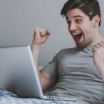 Laptop-Nutzer jubelt im Bett