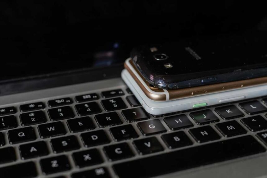 Three smartphones piled on a laptop keyboard